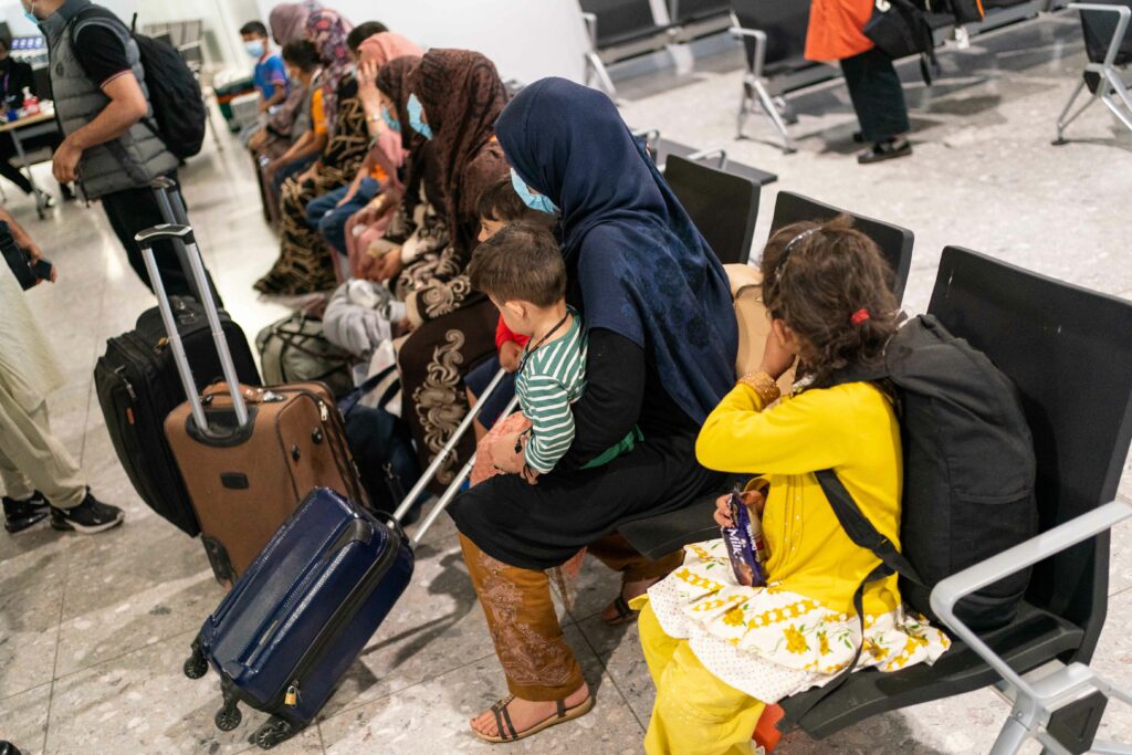 A group of afghani people sitting in chairs with luggage